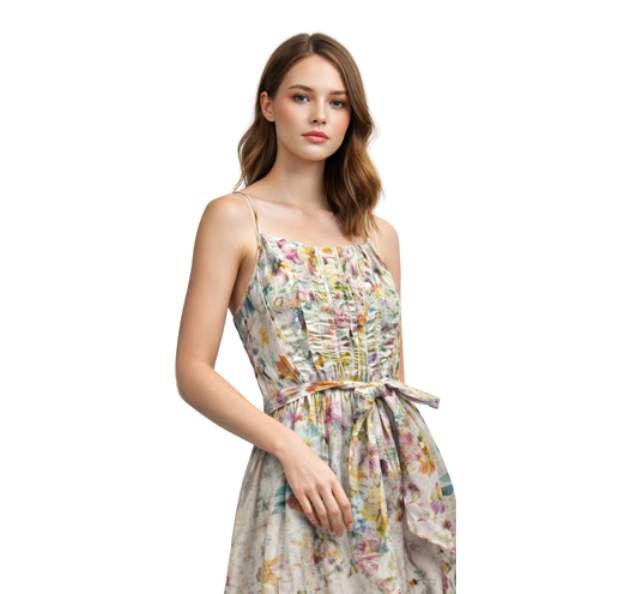 Young woman wearing a colorful sundress with thin straps and a bow tie at the waist. She looks poised, against a plain white background.